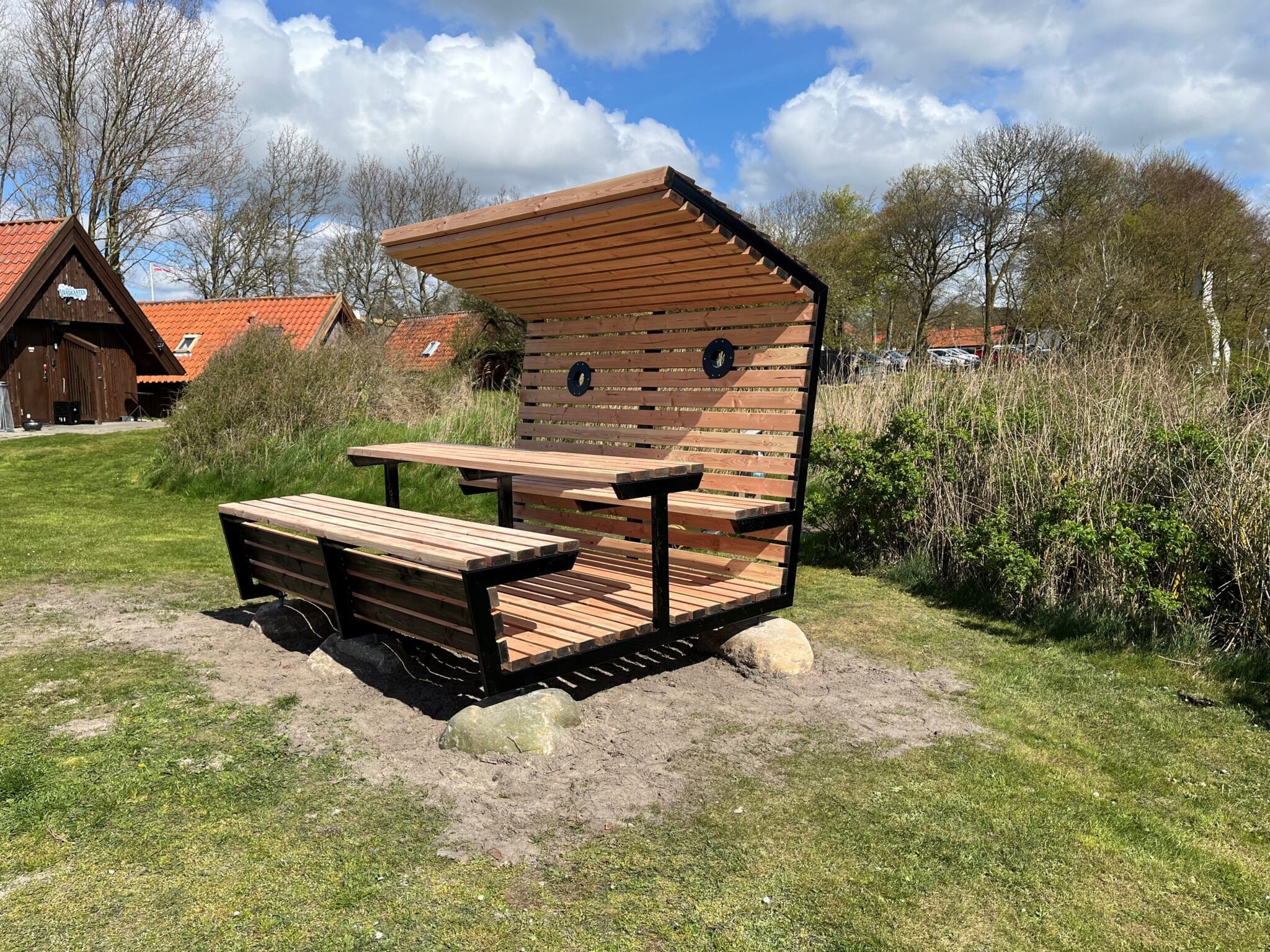 Hævet bordbænkesæt med halvåben overdækning hos Øhavsstien. Af ubehandlet douglas.