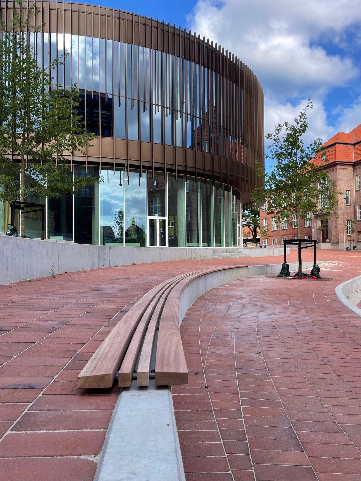 Buet plintesæde i ubehandlet sapele foran universitetsbygning i Aarhus – Inventarrum specialinventar.